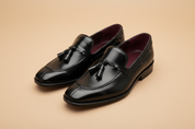 Par mocassins tassel preto polido — fundo bege studio
